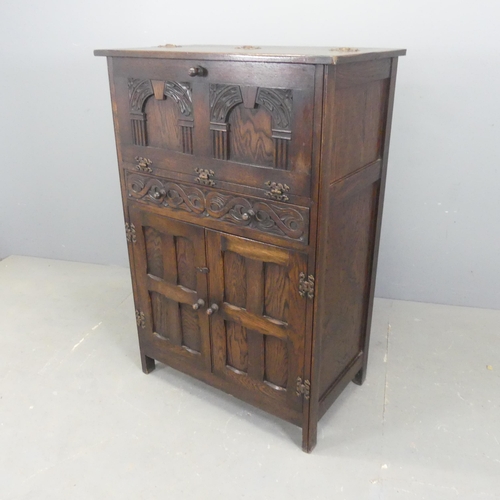 2519 - An early 20th century oak drinks cabinet, with lifting top and fall front revealing a mirrored singl... 