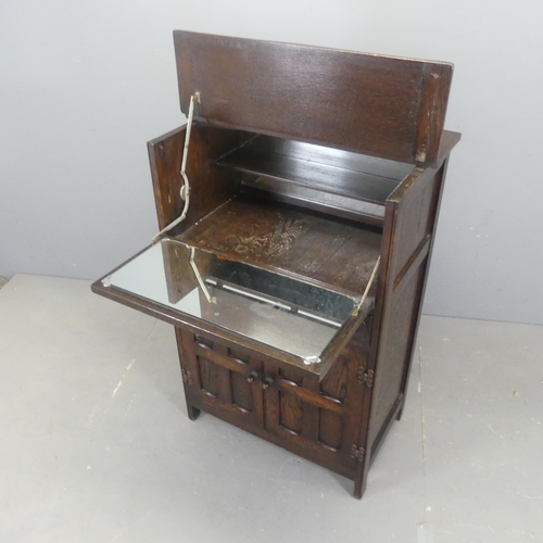 2519 - An early 20th century oak drinks cabinet, with lifting top and fall front revealing a mirrored singl... 