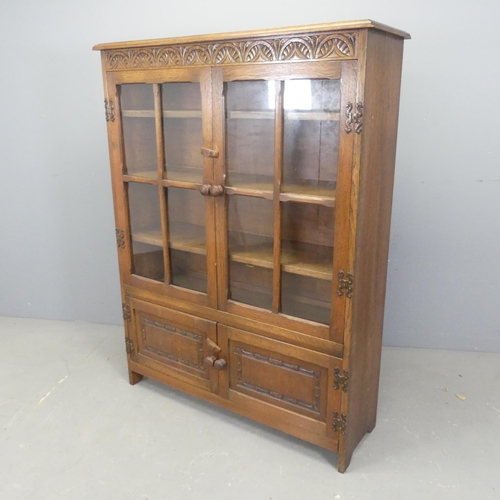 2544 - An early 20th century oak bookcase, with two glazed doors, cupboards under and carved decoration. Wi... 