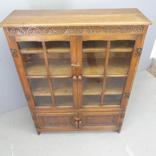 2544 - An early 20th century oak bookcase, with two glazed doors, cupboards under and carved decoration. Wi... 