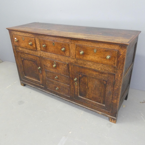 2570 - A 19th century oak sideboard, with six drawers, two panelled cupboard doors, and raised on stile leg... 