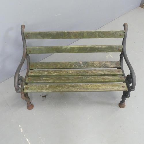 2633 - An antique teak slatted child's garden bench with painted cast iron ends. W86cm, H58cm, D47cm.