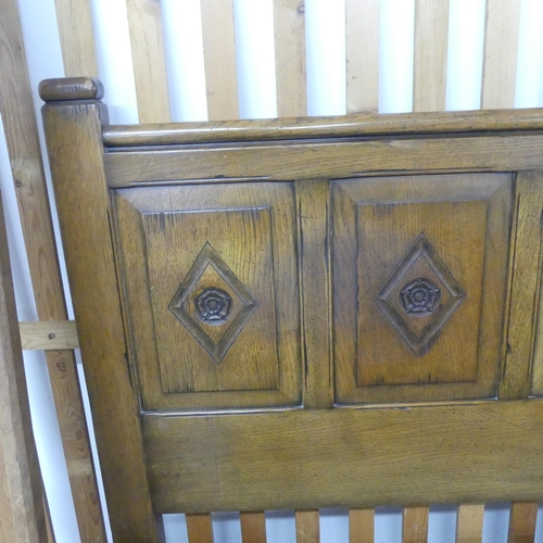 2647 - A reproduction oak King size 5ft bed, comprising panelled headboard with Tudor rose decoration, two ... 