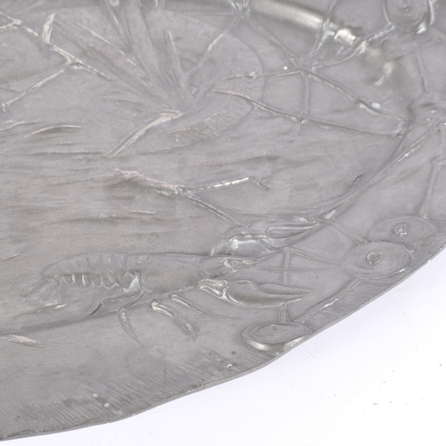 108 - An Art Nouveau pewter oval fish serving platter, repousse decorated with swimming fish, lobster, dia... 