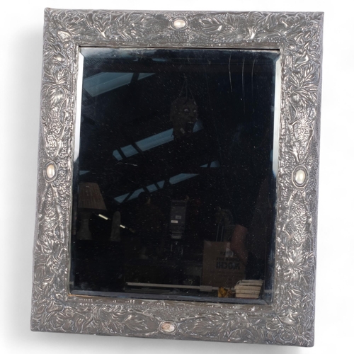 113 - An Art Nouveau pewter framed wall mirror, with floral repousse decoration and mother-of-pearl bosses... 