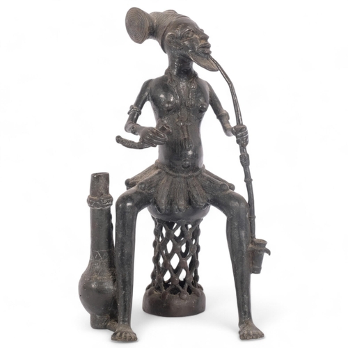 123 - A patinated bronze figure, Yiruba, Nigeria, study of a seated man smoking a pipe, H29cm