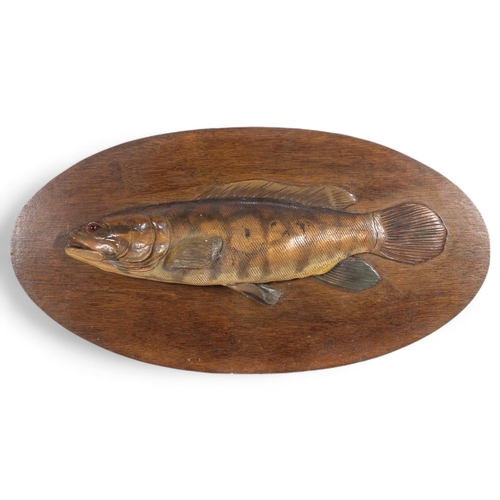 23 - An Antique wooden sculpture of a fish, bowfin, with glass eye, mounted on wooden oval plaque, unsign... 