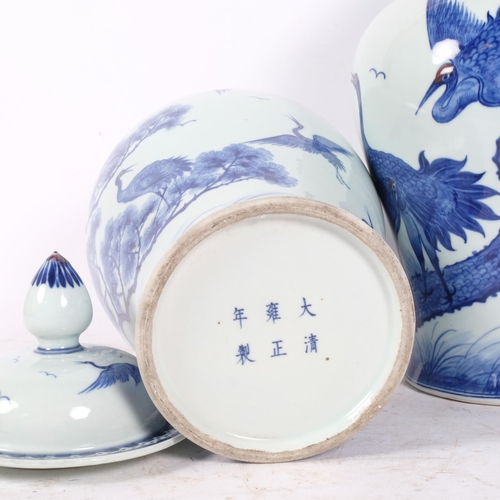 295 - A near pair of Chinese porcelain lidded jars with blue painted flying crane decoration, each bird wi... 