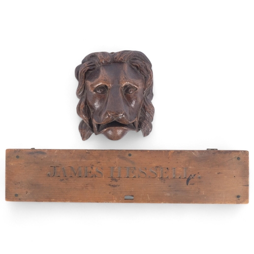 87 - A carved oak lion mask, H18cm, and a pine hinged panel named to James Hessell (2)