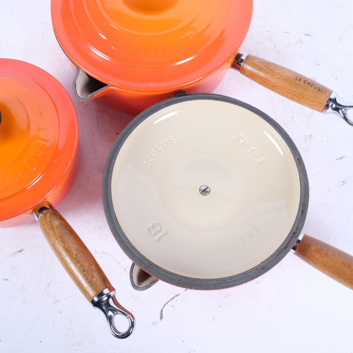 424 - LE CREUSET - a graduated set of 3 orange saucepans, largest diameter 20cm