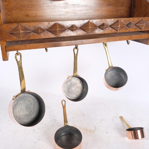 440 - A graduated set of 5 copper and brass saucepans, on wall-hanging rack, W41cm