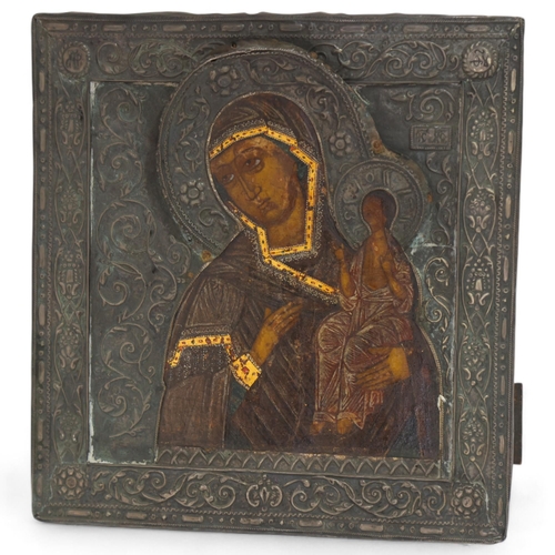 20 - An Antique Russian icon depicting the Mother of God, oil on wood panel with relief pierced silver ha... 