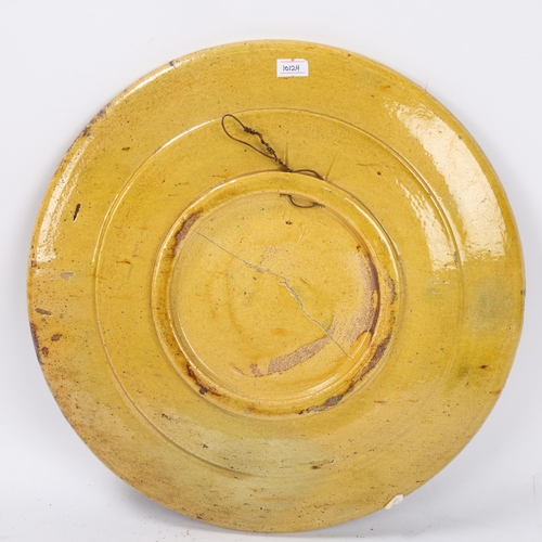 79 - An early lead glazed pottery charger with incised sunburst decoration surrounded by hearts, butterfl... 