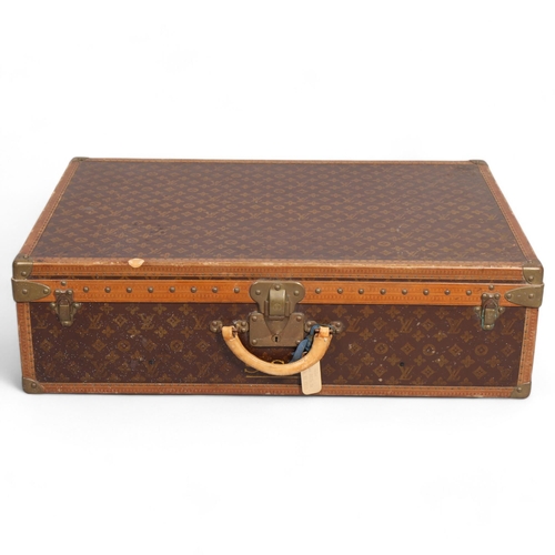 167 - LOUIS VUITTON - a hard suitcase/trunk with monogrammed fabric cover, leather edging, brass locks and... 