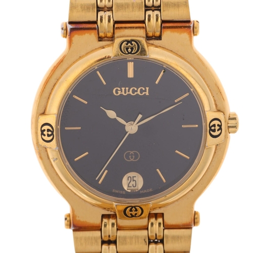 1048 - GUCCI - a gold plated 9200M quartz calendar bracelet watch, black dial with gilt baton hour markers,... 