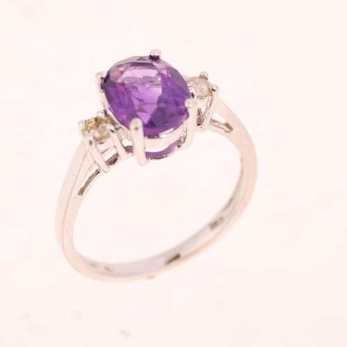 1437 - A 14ct white gold three stone amethyst and diamond ring, claw set with oval mixed-cut amethyst and m... 