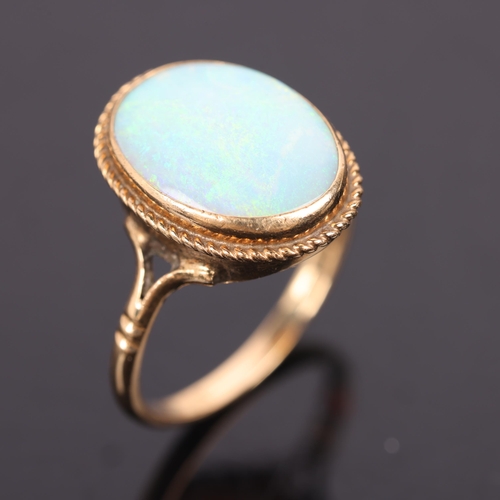 1524 - A 9ct gold single stone opal dress ring, set with oval cabochon opal within rope twist surround, set... 