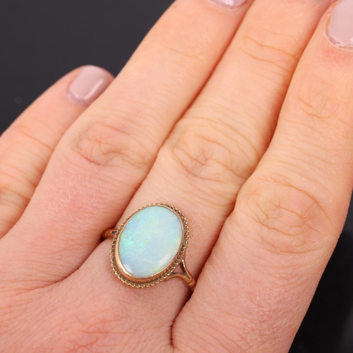 1524 - A 9ct gold single stone opal dress ring, set with oval cabochon opal within rope twist surround, set... 