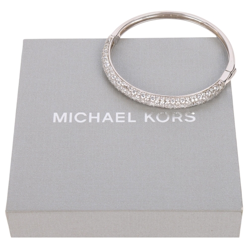 1595 - MICHAEL KORS - a modern designer sterling silver cubic zirconia hinged bangle, signed MK, band width... 