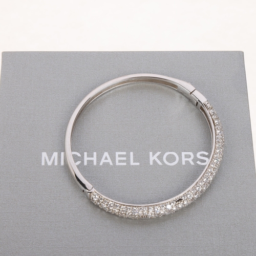 1595 - MICHAEL KORS - a modern designer sterling silver cubic zirconia hinged bangle, signed MK, band width... 