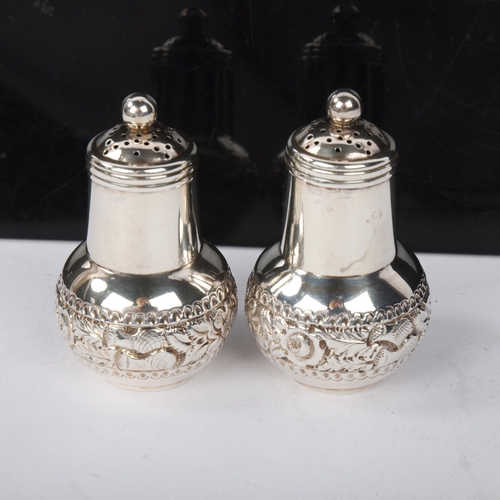 1838 - A pair of late Victorian silver 'Thistle' pepperettes, Sibray, Hall & Co, London 1892, with relief e... 