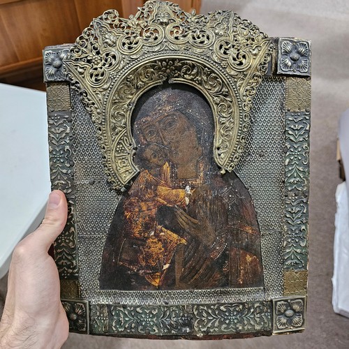 19 - An Antique Russian icon depicting the Mother of God, oil on wood panel with relief pierced silver ha... 