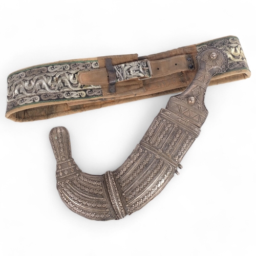 42 - An Antique Jambiya dagger with sheath, length approx 40cm, and ceremonial fabric belt (2)