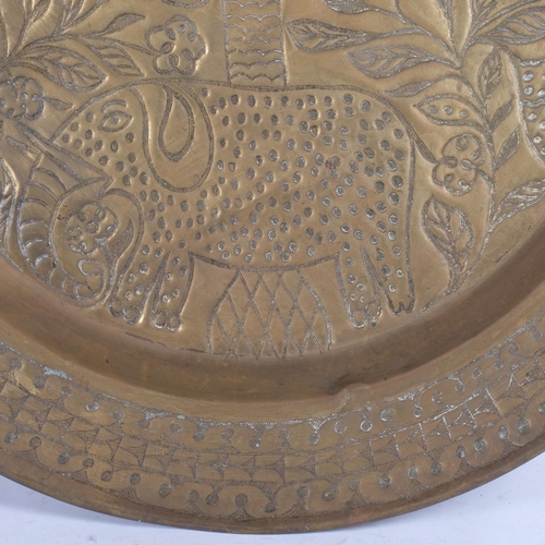 55 - A large Indian brass charger/wall plate, with allover boss decoration depicting an elephant and flow... 