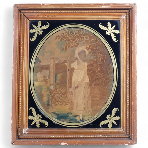 59 - A 19th century silk work oval panel, depicting a lady in a bonnet feeding a sheep, gilt-framed, 44cm... 