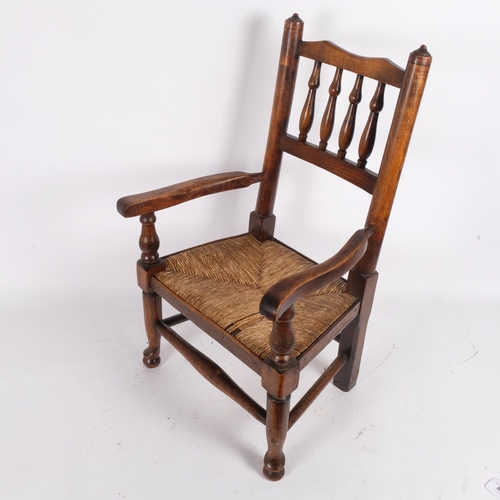 80 - A child's Lancashire design elbow chair, with spindle back and rush seat