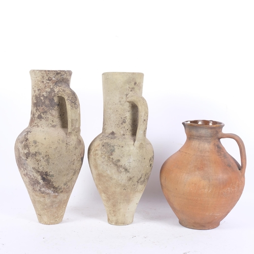 207 - A pair of single-handled pottery ewers, and a terracotta jug