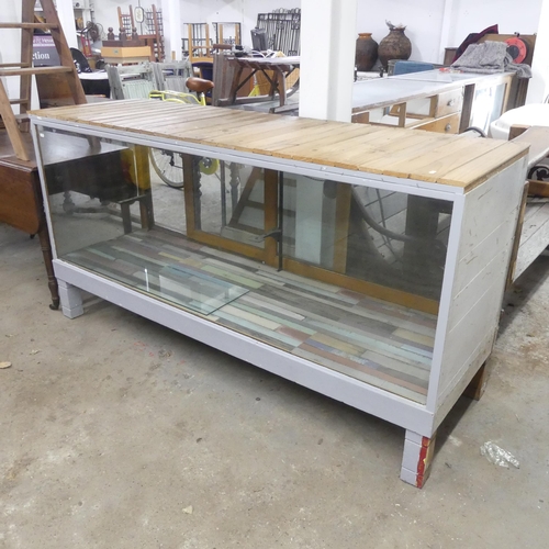 2669 - A vintage shop display cabinet, with slatted pine top and single adjustable glass shelf. Width 183cm... 