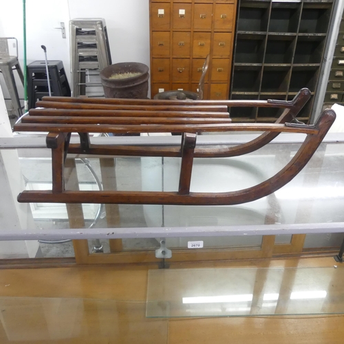 2672 - A small slatted teak sledge. Length 85cm, height 26cm, width 33cm.