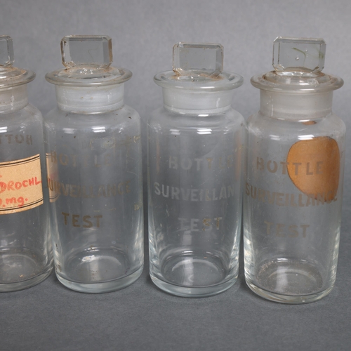 3005 - A group of nine clear glass etched surveillance test bottles with stoppers, some with labels, includ... 