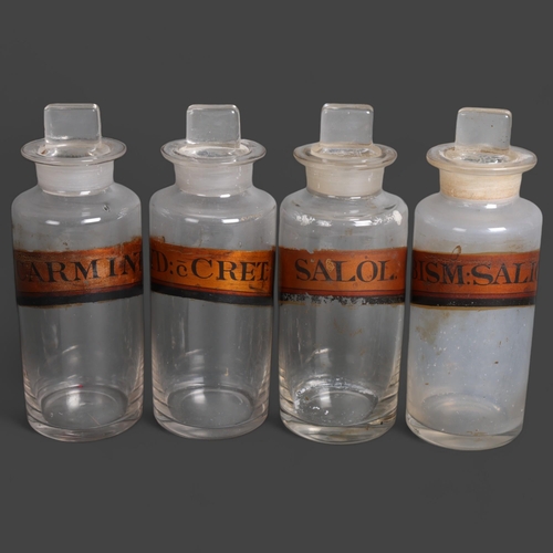 3008 - A group of four clear glass apothecary bottles, each with stopper, all have gold gilt period labels,... 