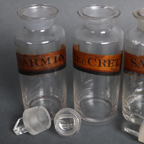 3008 - A group of four clear glass apothecary bottles, each with stopper, all have gold gilt period labels,... 