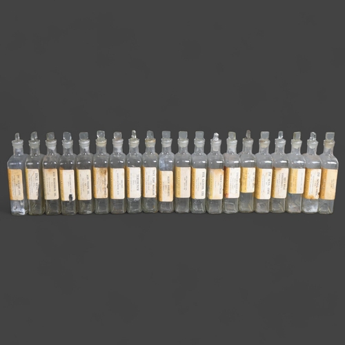 3019 - A group of 20 rectangular clear glass apothecary bottles, all with stoppers, each with period paper ... 