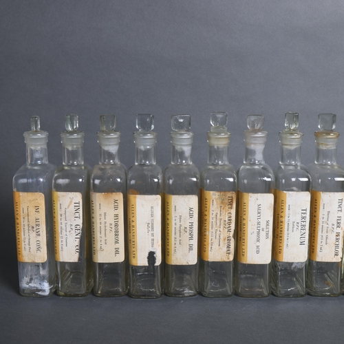 3019 - A group of 20 rectangular clear glass apothecary bottles, all with stoppers, each with period paper ... 