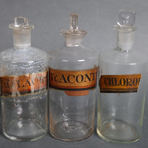 3021 - A group of six clear glass apothecary bottles, each with stoppers, all have period gilt gold labels,... 