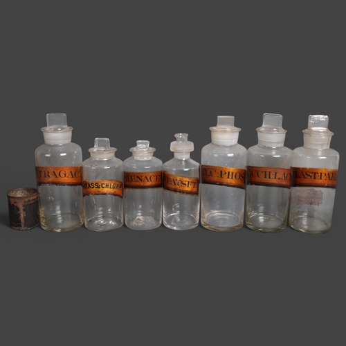 3026 - A group of seven mixed clear glass bottles, each with stoppers, all have gilt gold period labelling,... 