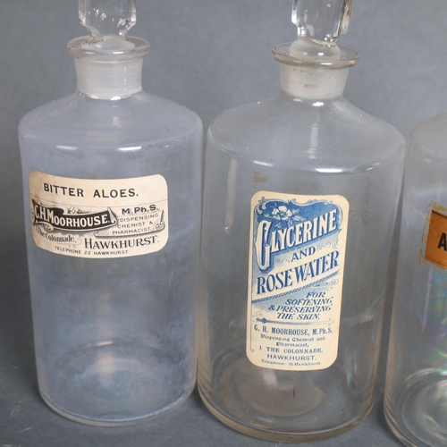 3029 - A group of four clear glass apothecary bottles, each with stopper, all with period paper labelling, ... 