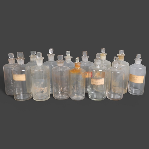 3030 - A group of 14 clear glass apothecary bottles, each with stopper, several have hand written period pa... 