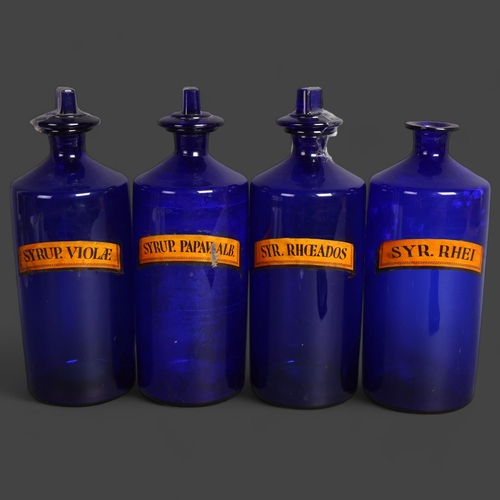 3045 - A group of four large blue glass apothecary bottles, three with stoppers, each with paper labels, la... 