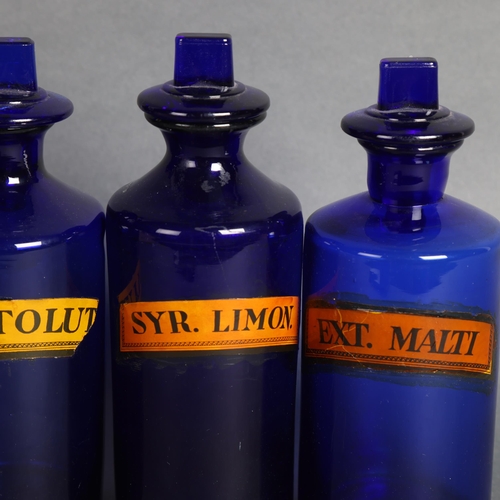 3047 - A group of four blue glass apothecary bottles with stoppers, each has paper label, largest height 22... 