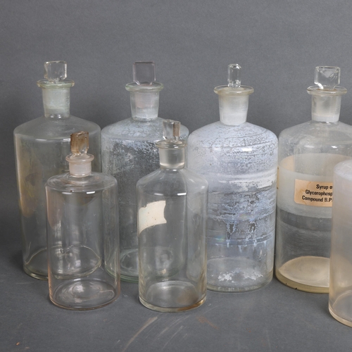 3063 - A quantity of clear glass apothecary bottles, all with stoppers, several with hand written period la... 