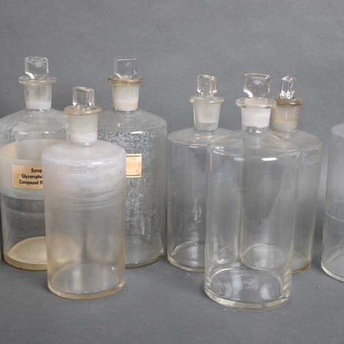 3063 - A quantity of clear glass apothecary bottles, all with stoppers, several with hand written period la... 