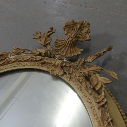 2710 - A pair of gilt-painted oval wall mirrors with sconces and pediments. Width 46cm, height 70cm.