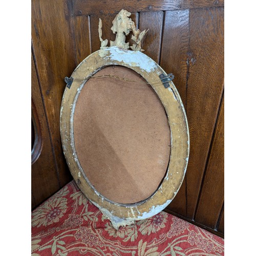 2710 - A pair of gilt-painted oval wall mirrors with sconces and pediments. Width 46cm, height 70cm.