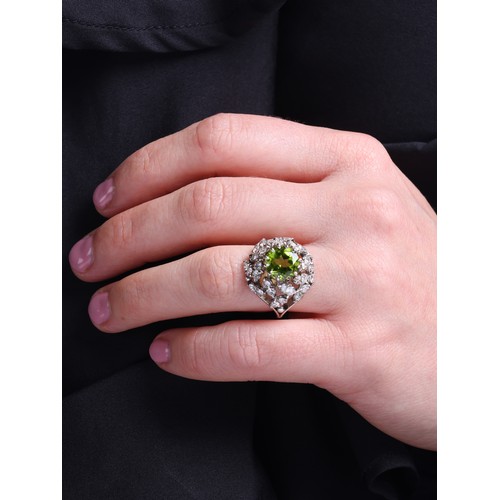 77 - A Peridot and Diamond Cocktail Ring, 

circa 1950, the bombe cluster centrally claw set with a round... 