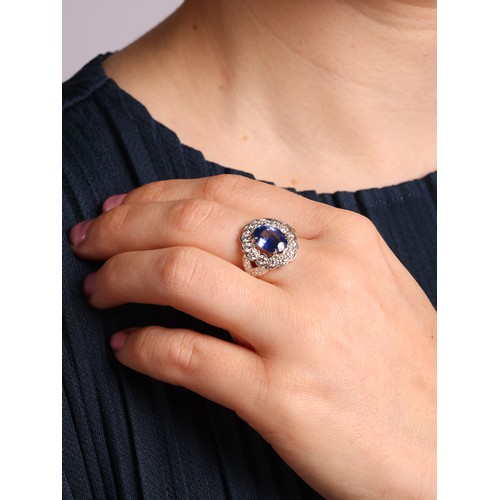 71 - A Sapphire and Diamond Cluster Ring,

the oval flowerhead cluster panel set with an oval mixed cut s... 